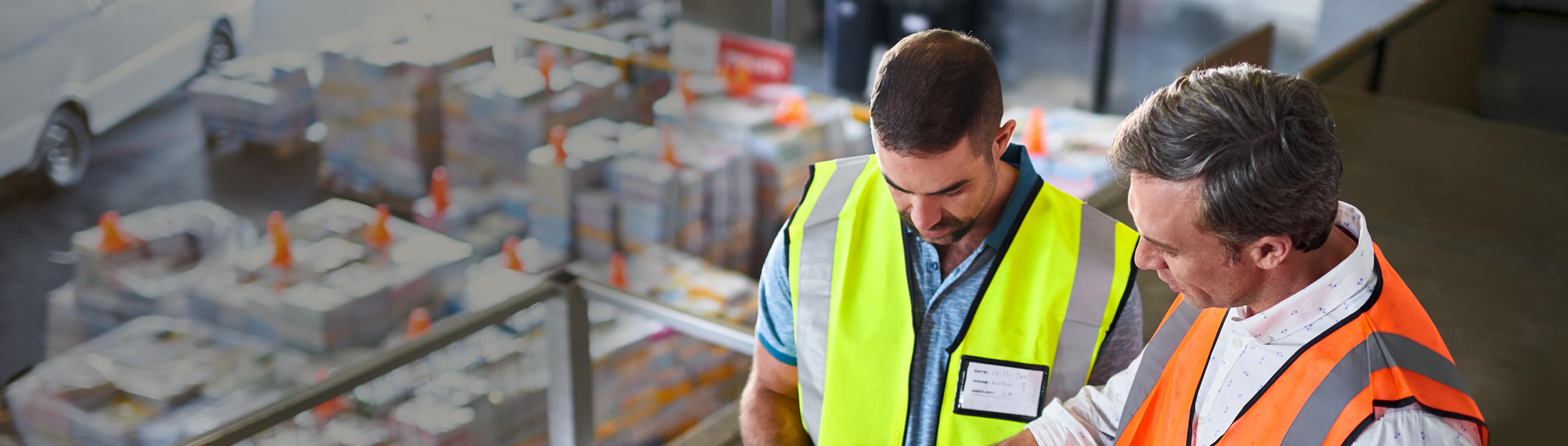 Two men in high vis checking their shipping schedule in a factory
