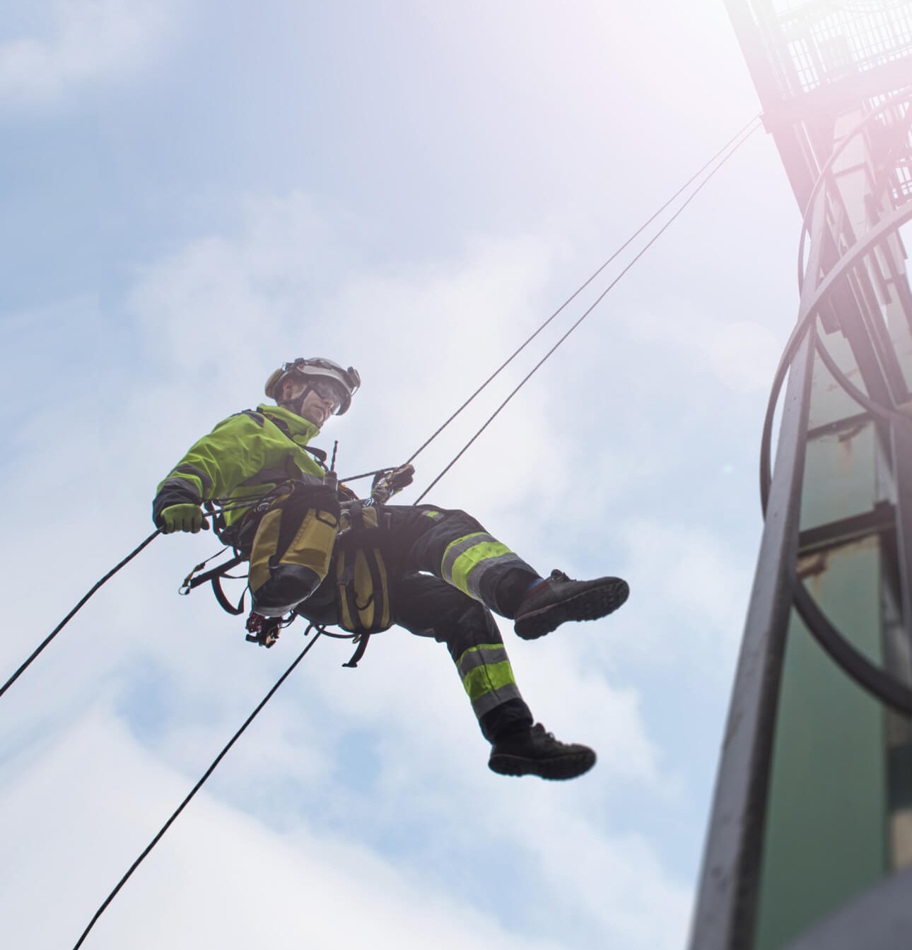 Manual rope access technician - worker abseil from tower - antenna in sun
